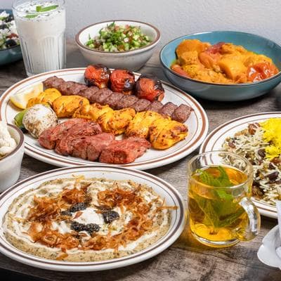 Persian kabob platter with grilled tomatoes, rice, and accompanying dishes
